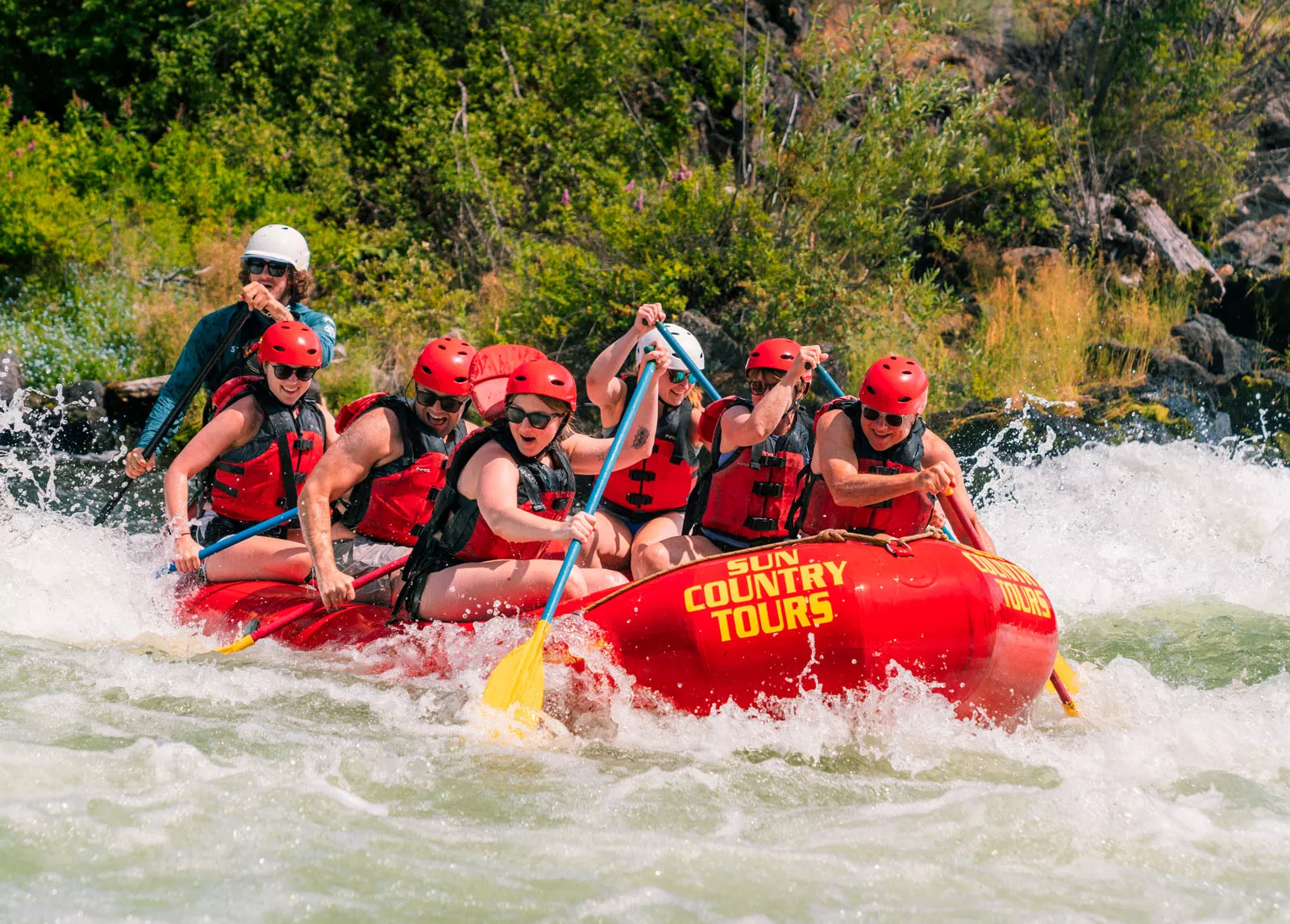 Group of people paddling on a red raft in a river