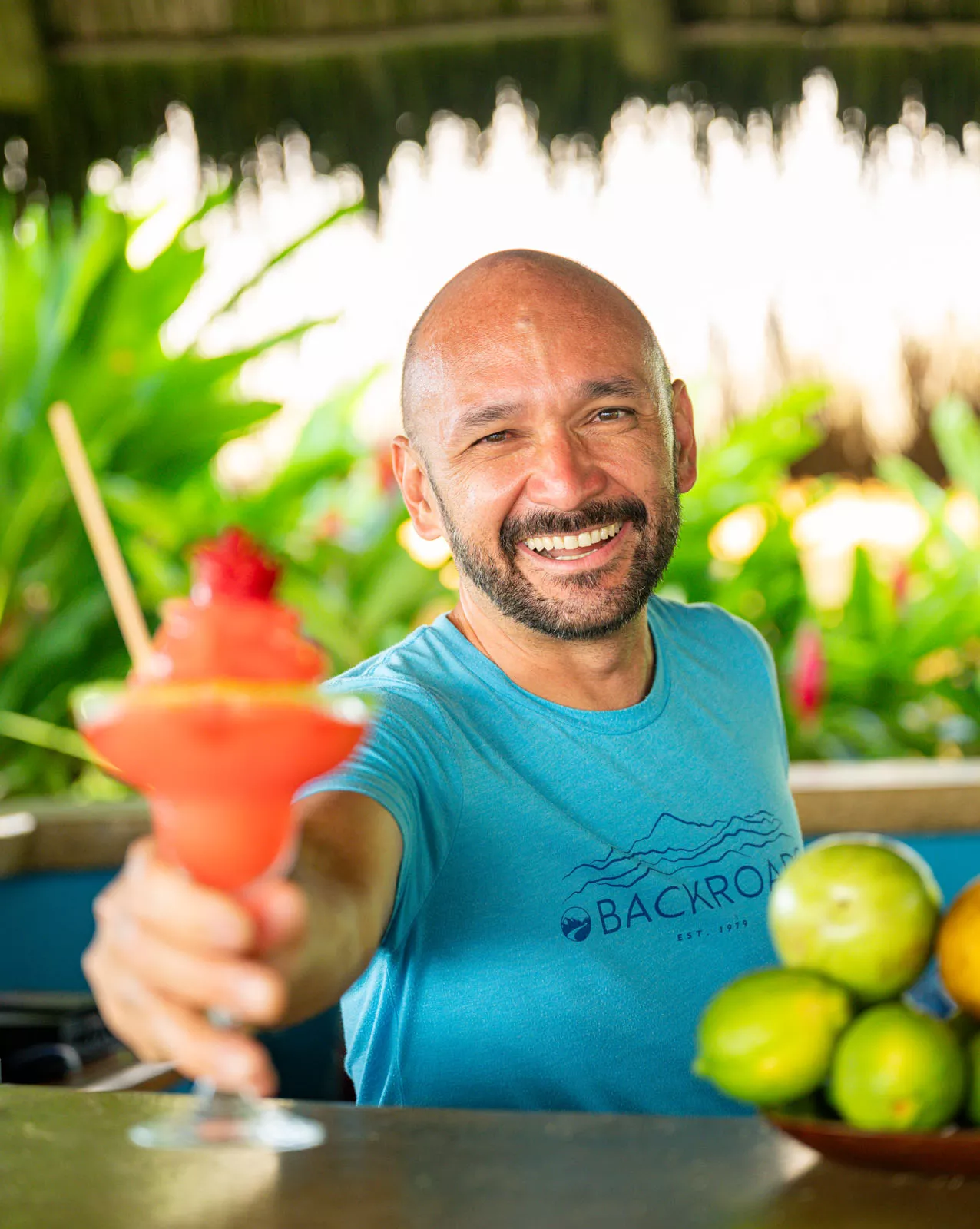 Man smiling while holding out a blended, red drink