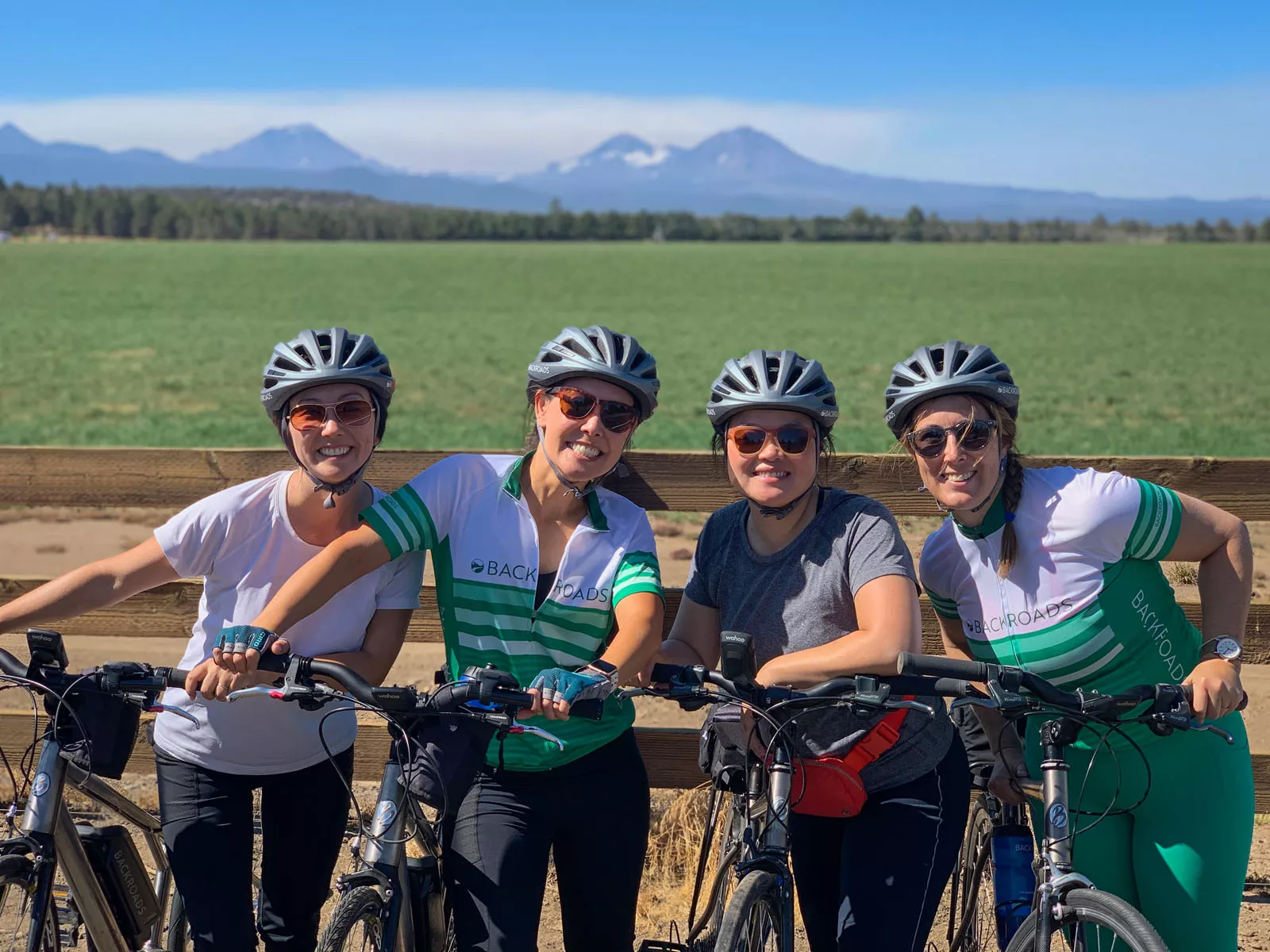 Group of four women smiling while standing next to their bikes