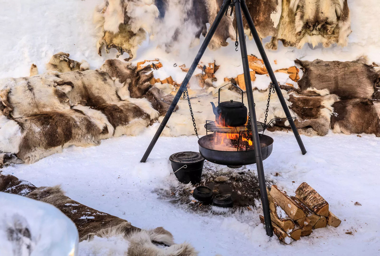 Kettle over a campfire and grill in the middle of a snowy field