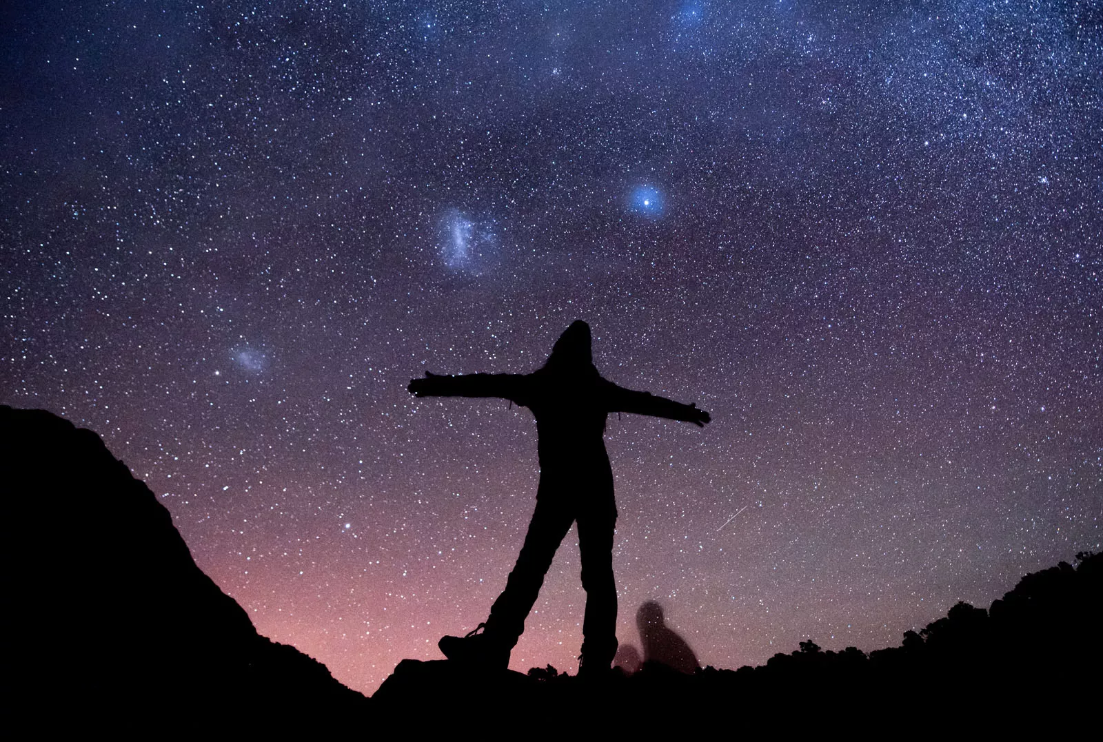 Silhouette of woman with her arms open with the stars in the sky