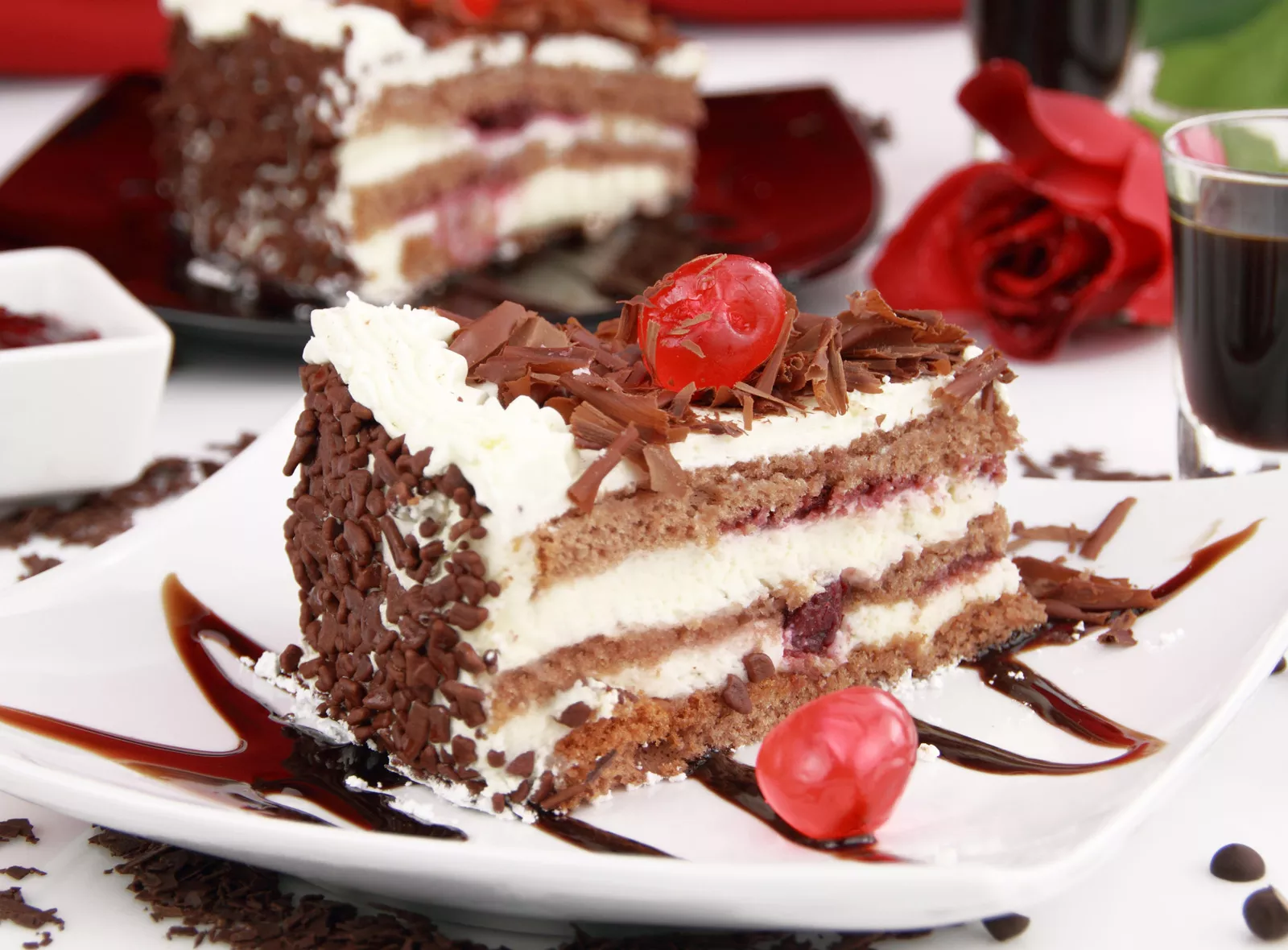 Chocolate cake on a white plate with red cherries on top