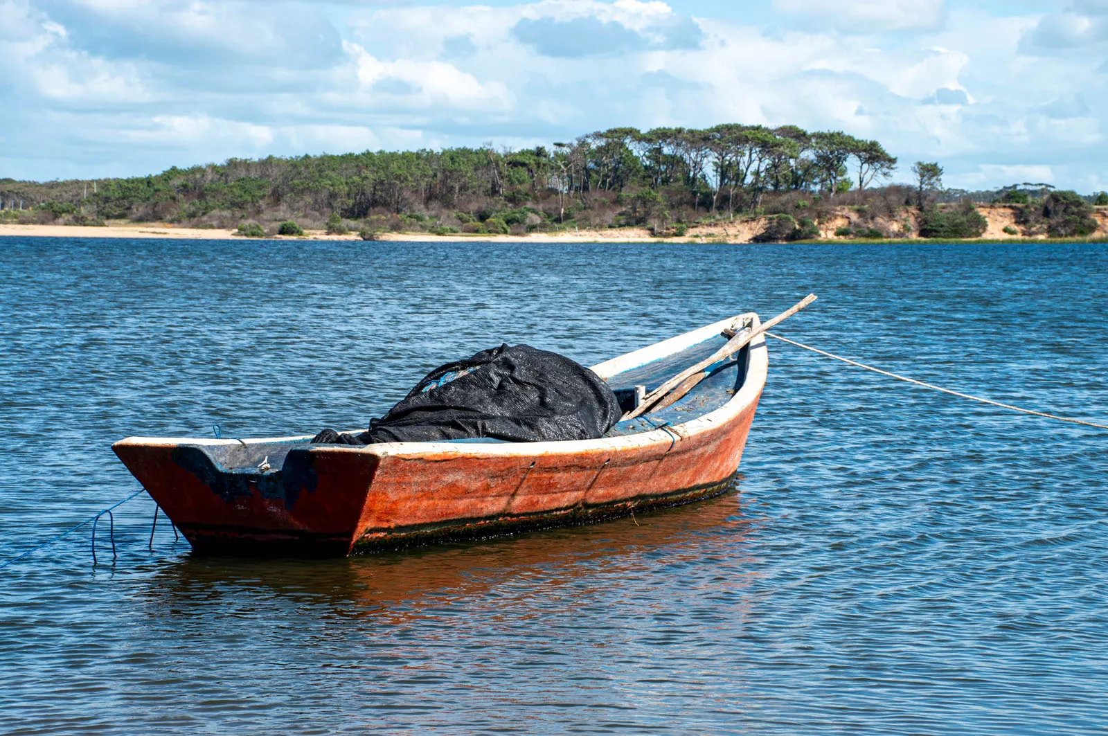 Small, wooden boat with a black tarp in the center
