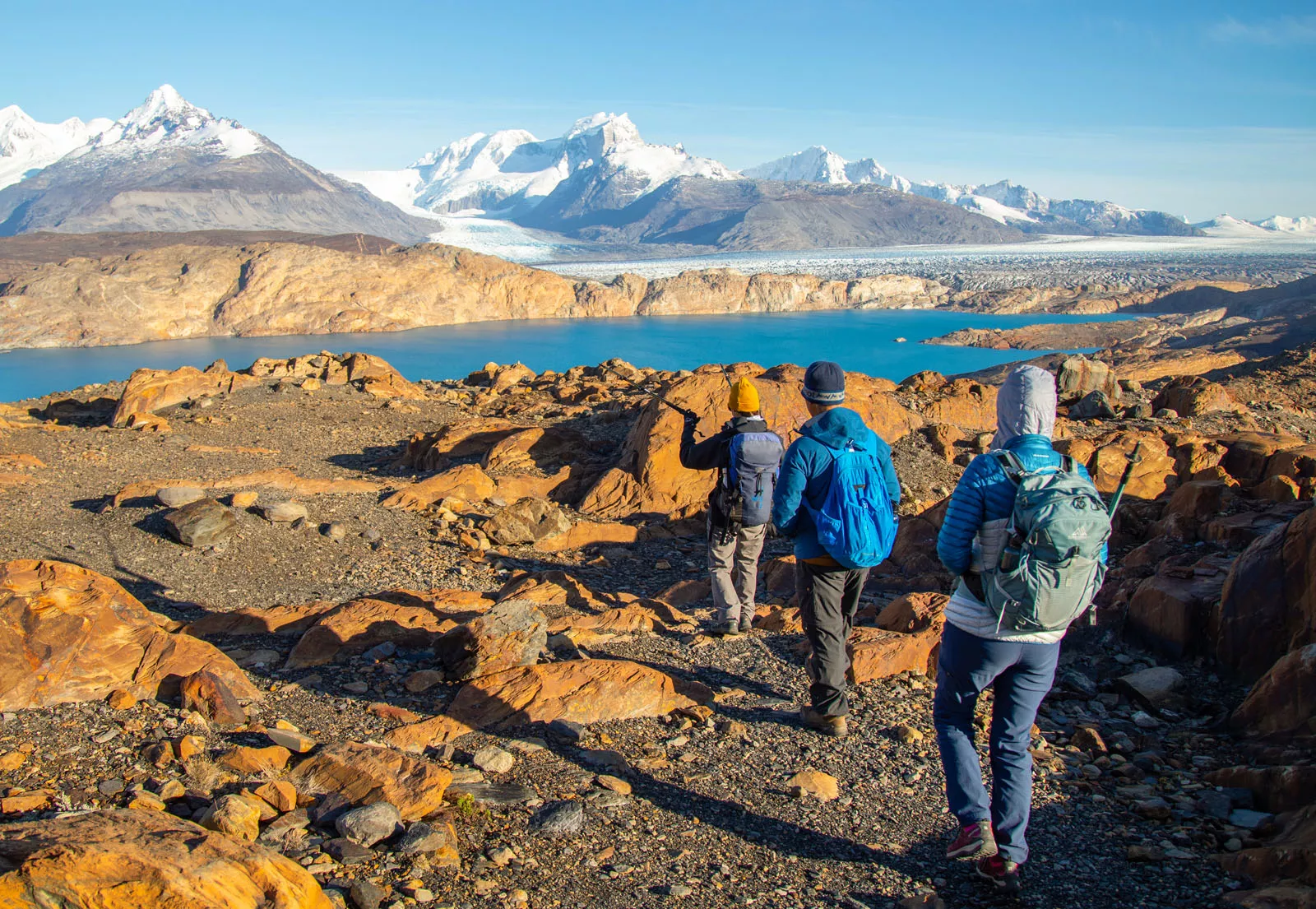 Three people walking on gravel trails towards a lake