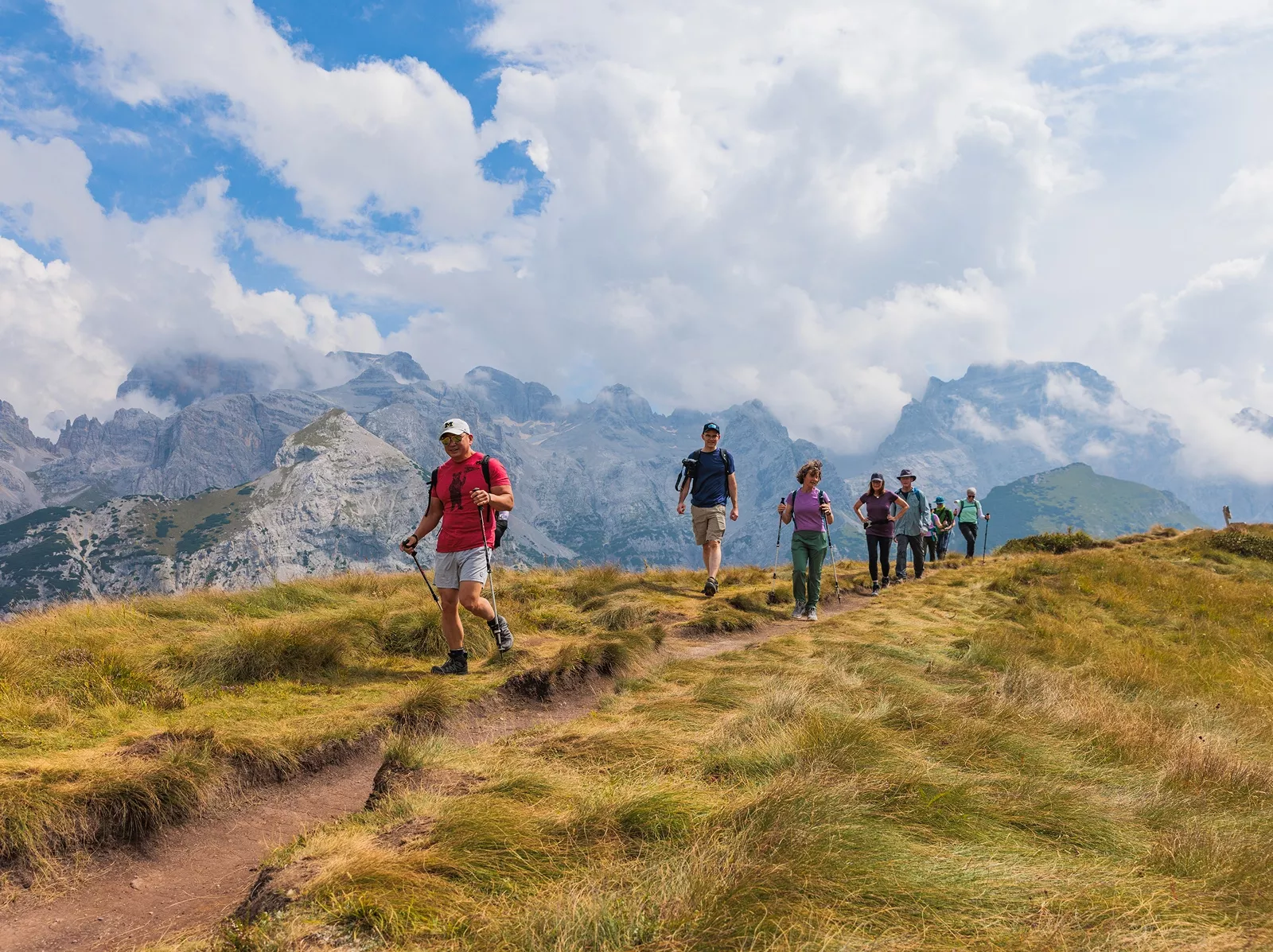 Group of people descending a dirt trail in the middle of a valley