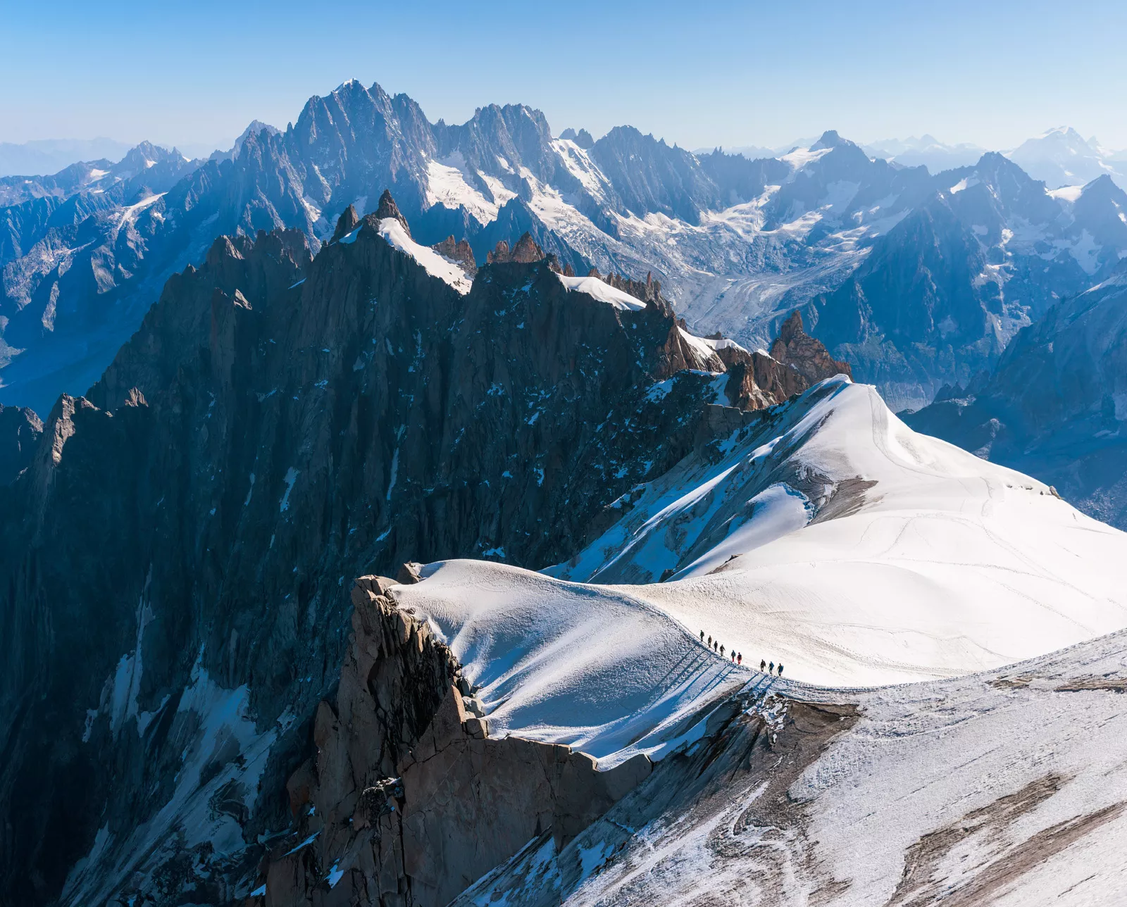 Top view of snowcapped mountains with larger mountains in the distance