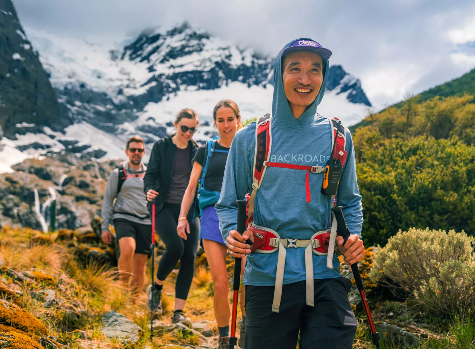 Two men and women hiking on a trail with foggy mountains in the background