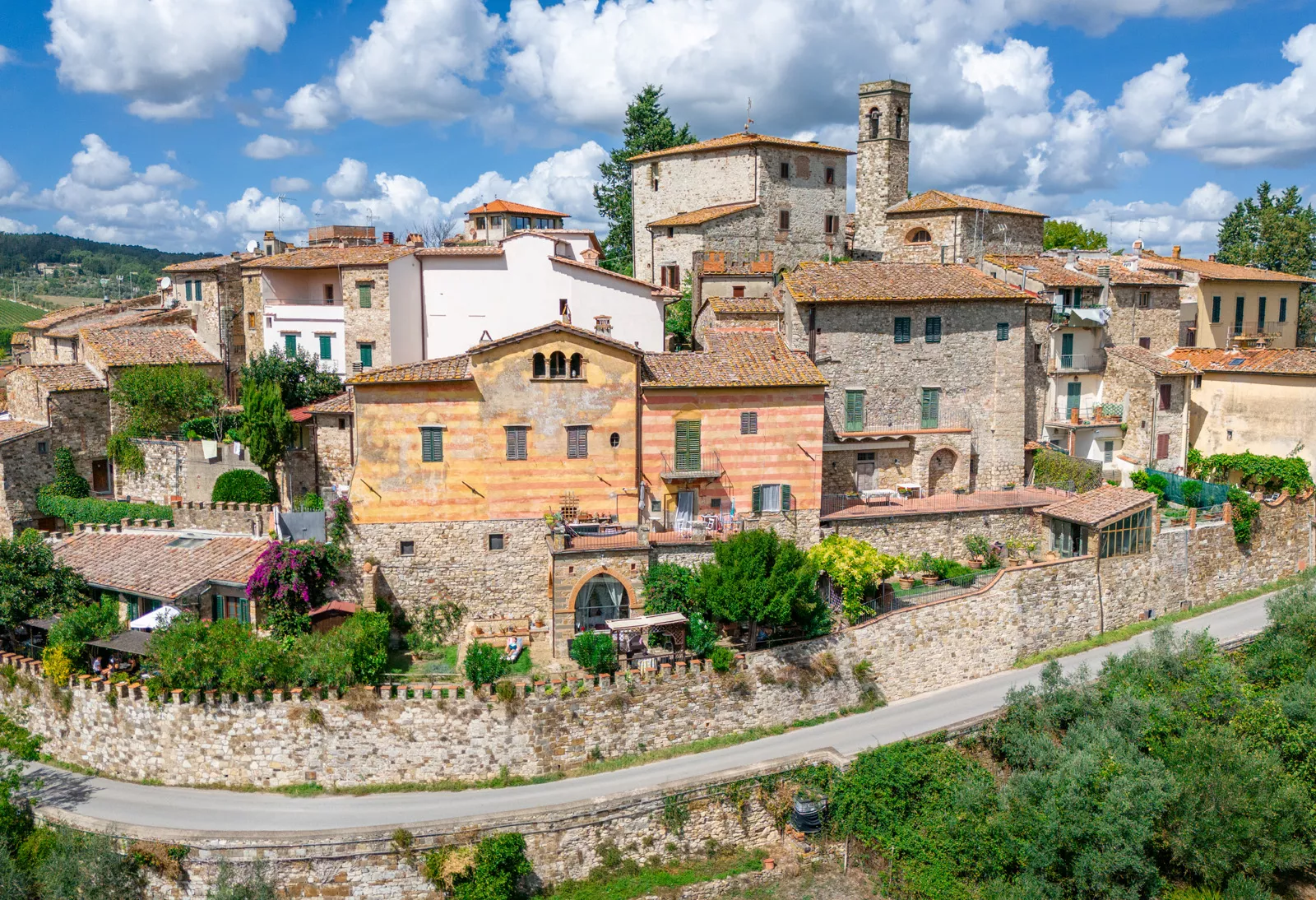 Exterior view of stone buildings along a road, with trees in front