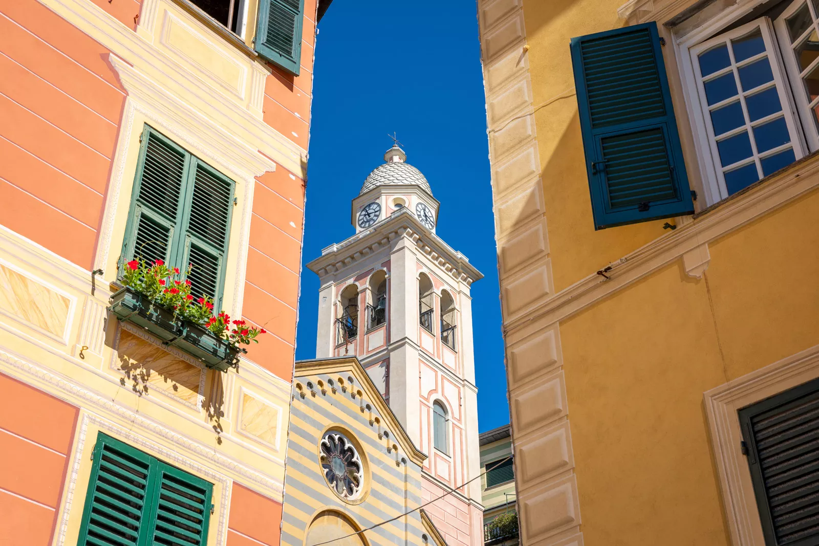 Orange buildings in the middle of a town, with a tall church bell tower in the center