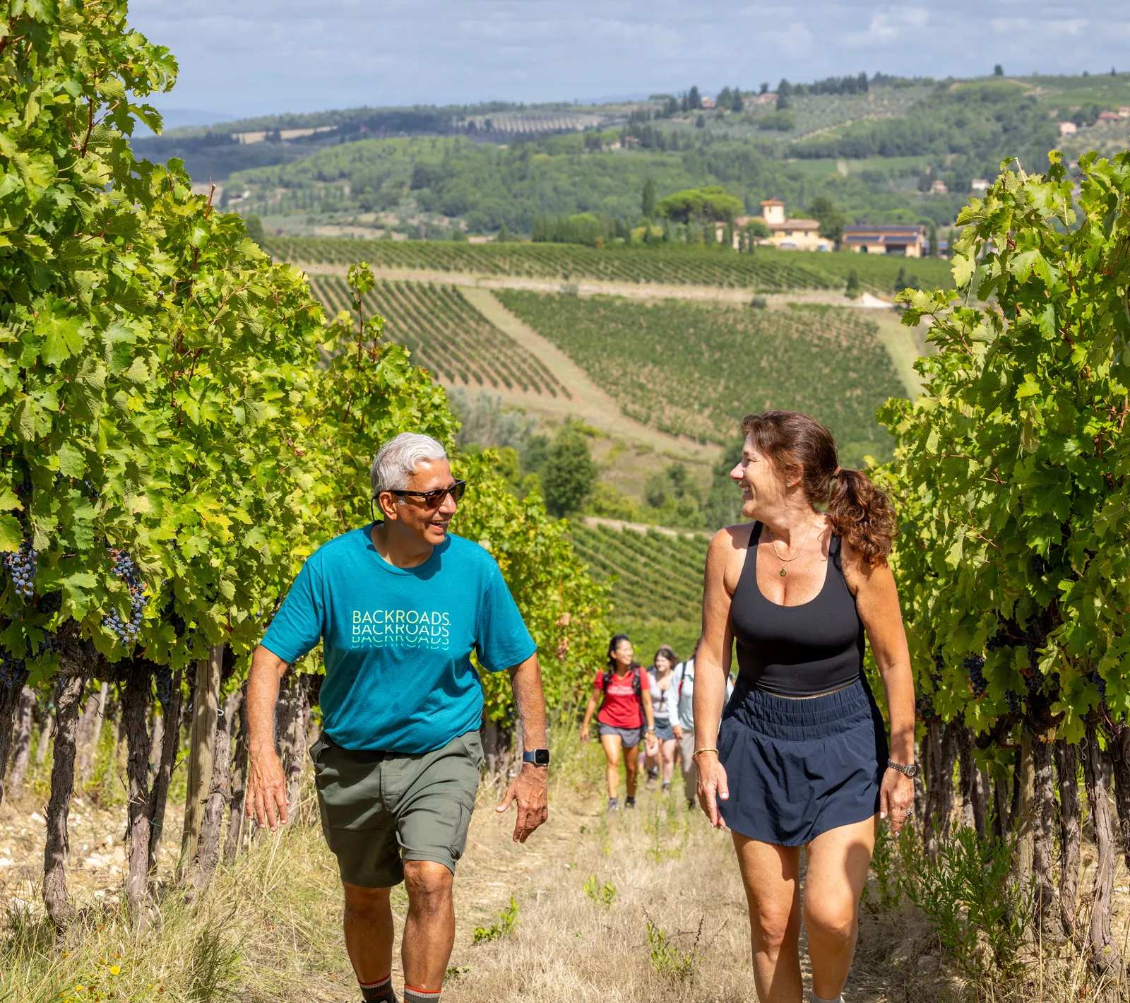 Man and woman smiling while walking through a field of crops