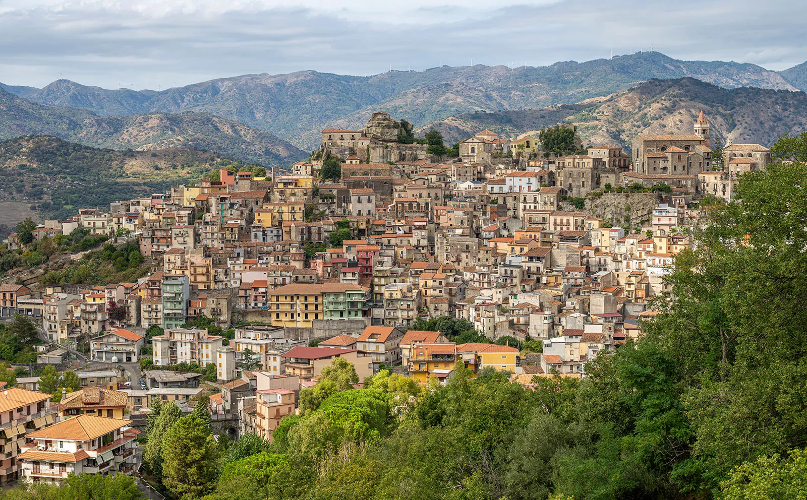 Large homes and apartment buildings along a hill, with mountains in the distance