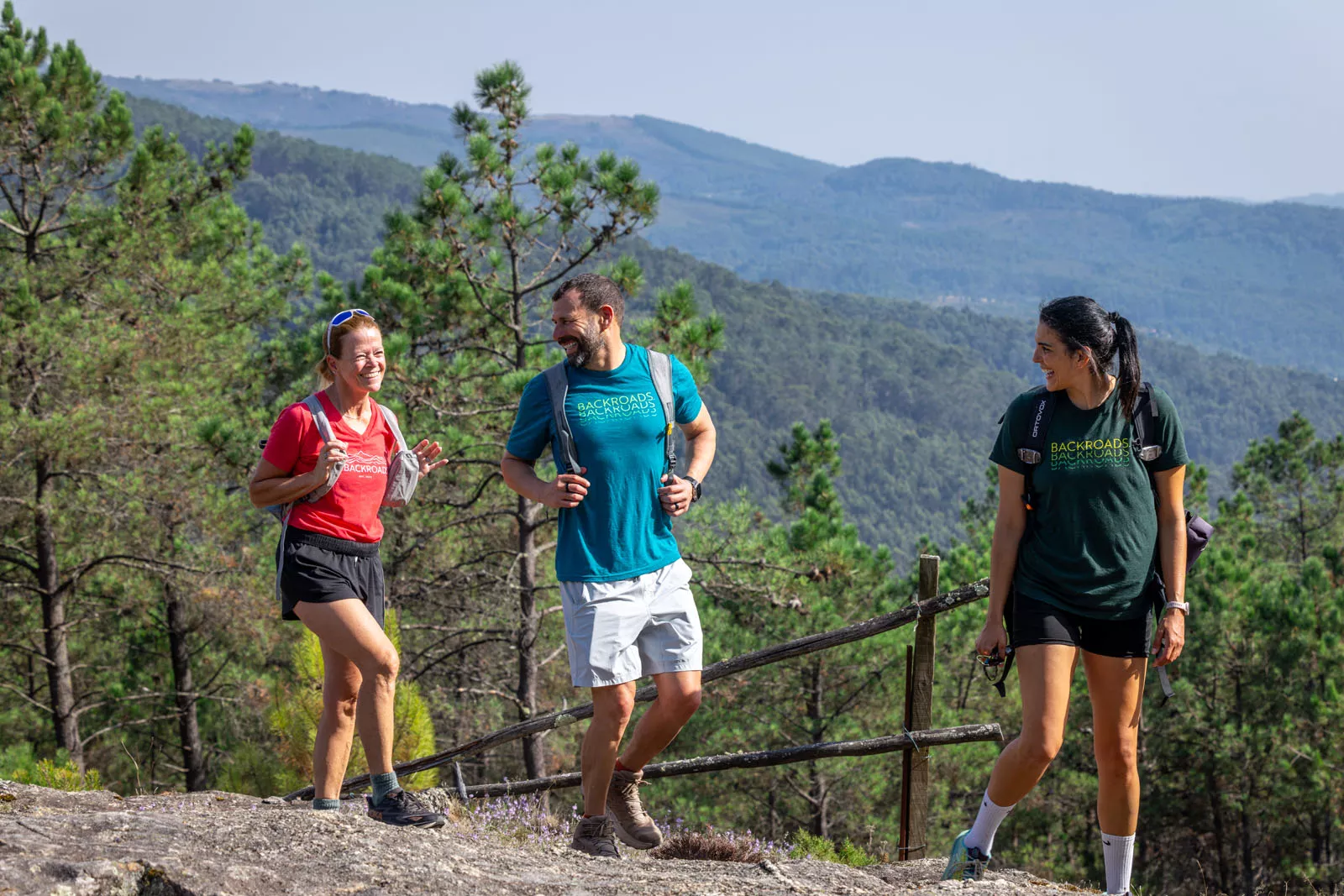 Man and two women smiling while hiking on top of a hill