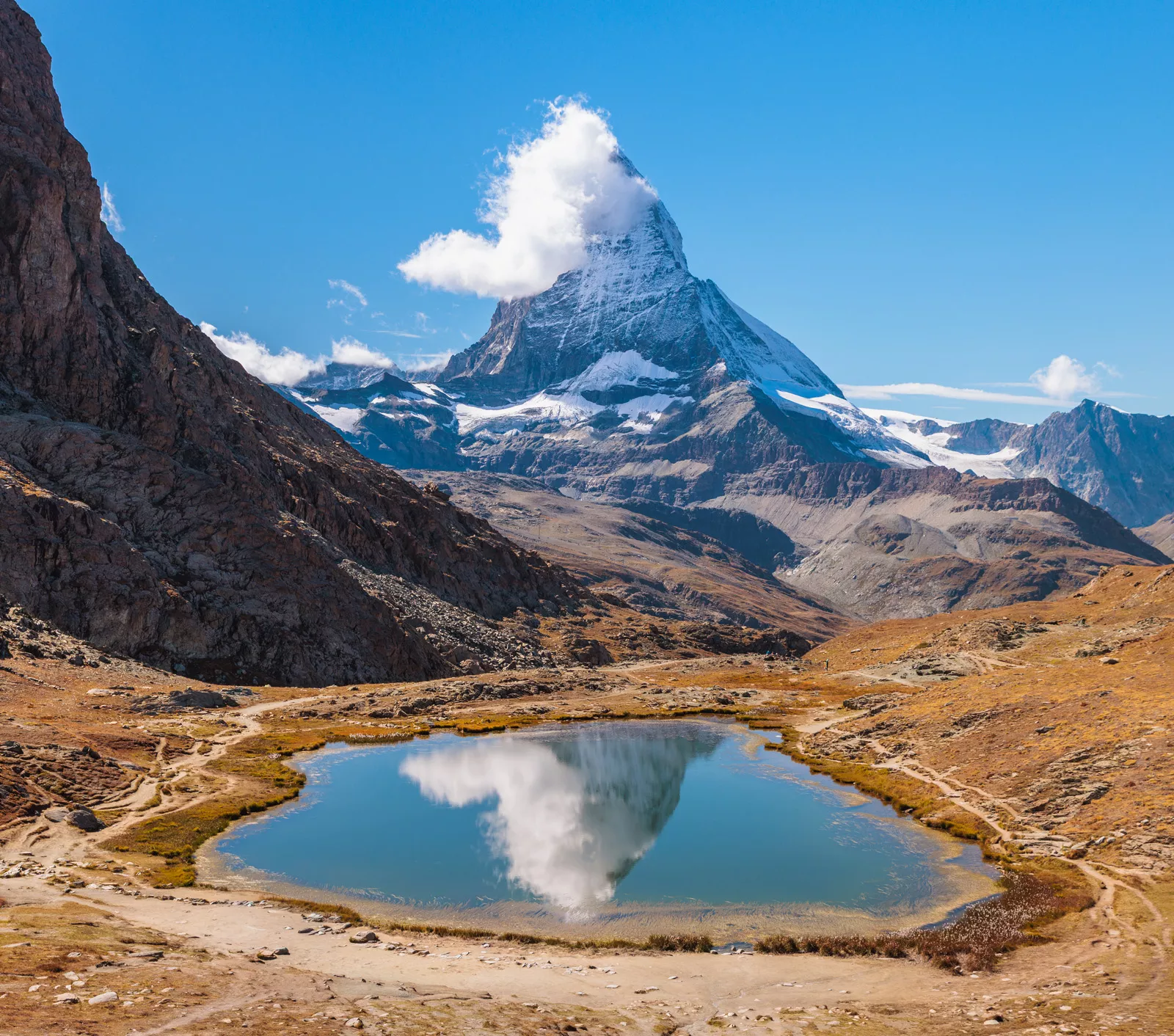 snow covered mountain with lake in front
