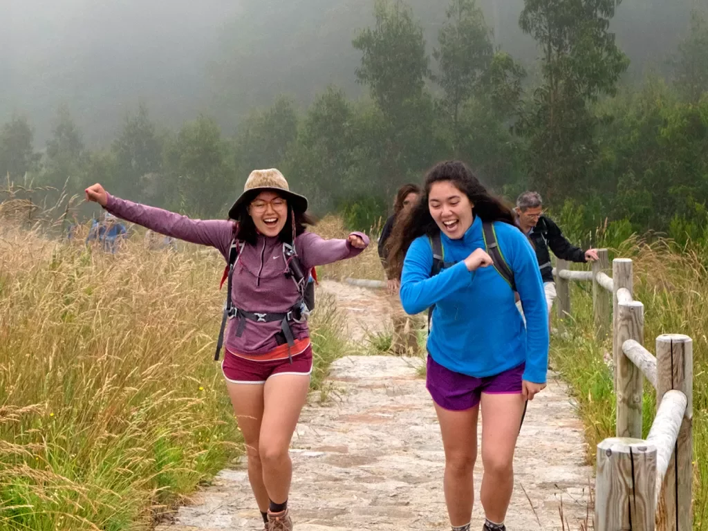 Hikers doing celebratory poses on trail.