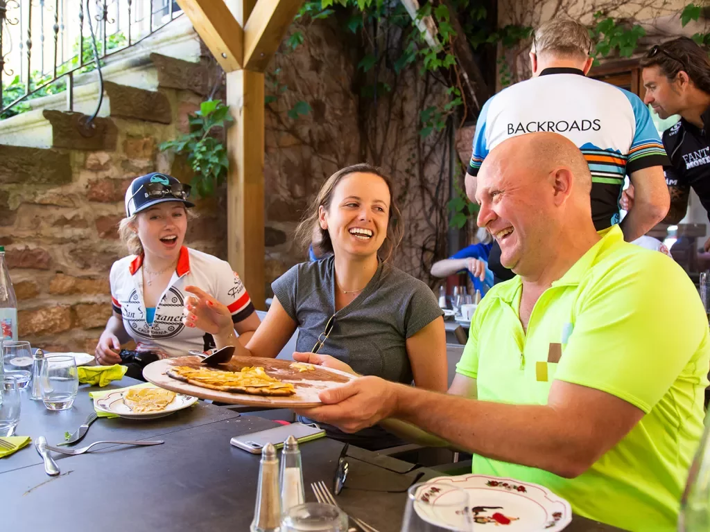 Backroads Guests Laughing Over Pizza in Alsace