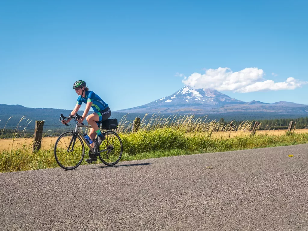 Guest riding down grassy road, Mount Hood in background.
