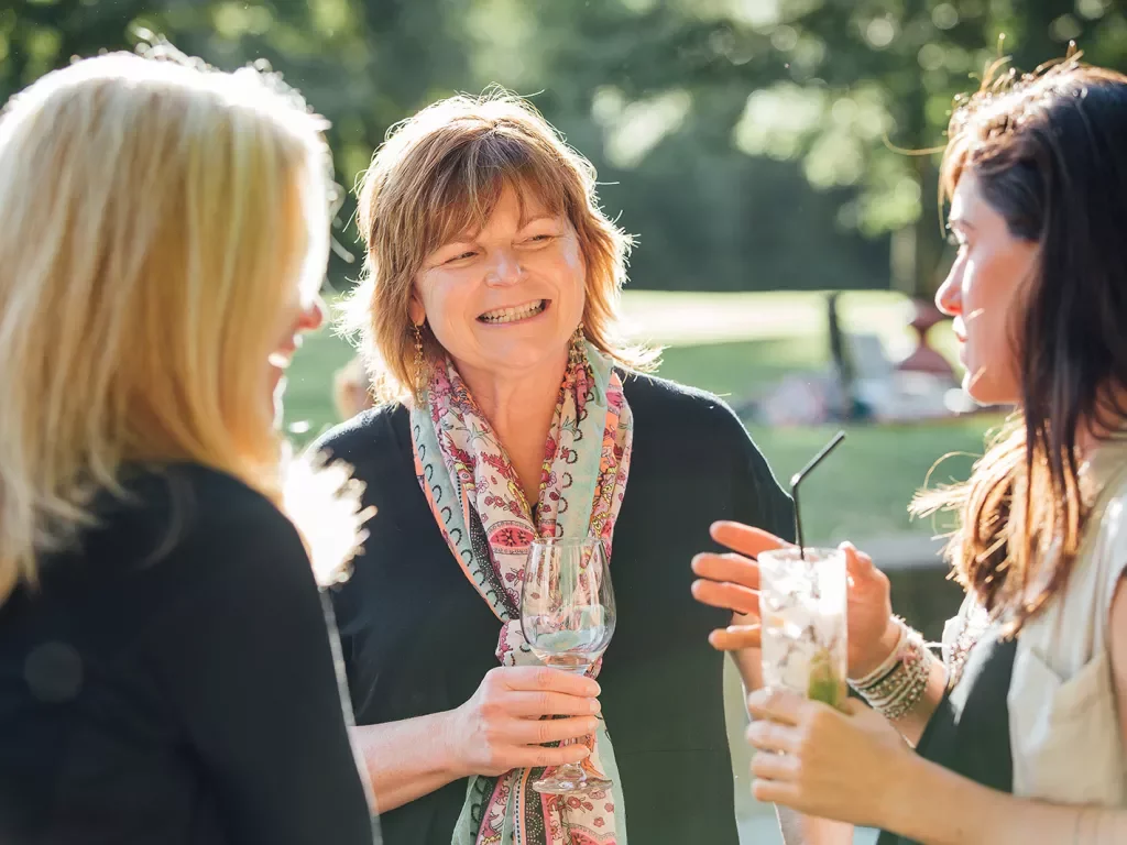 Three women having a conversation over drinks.