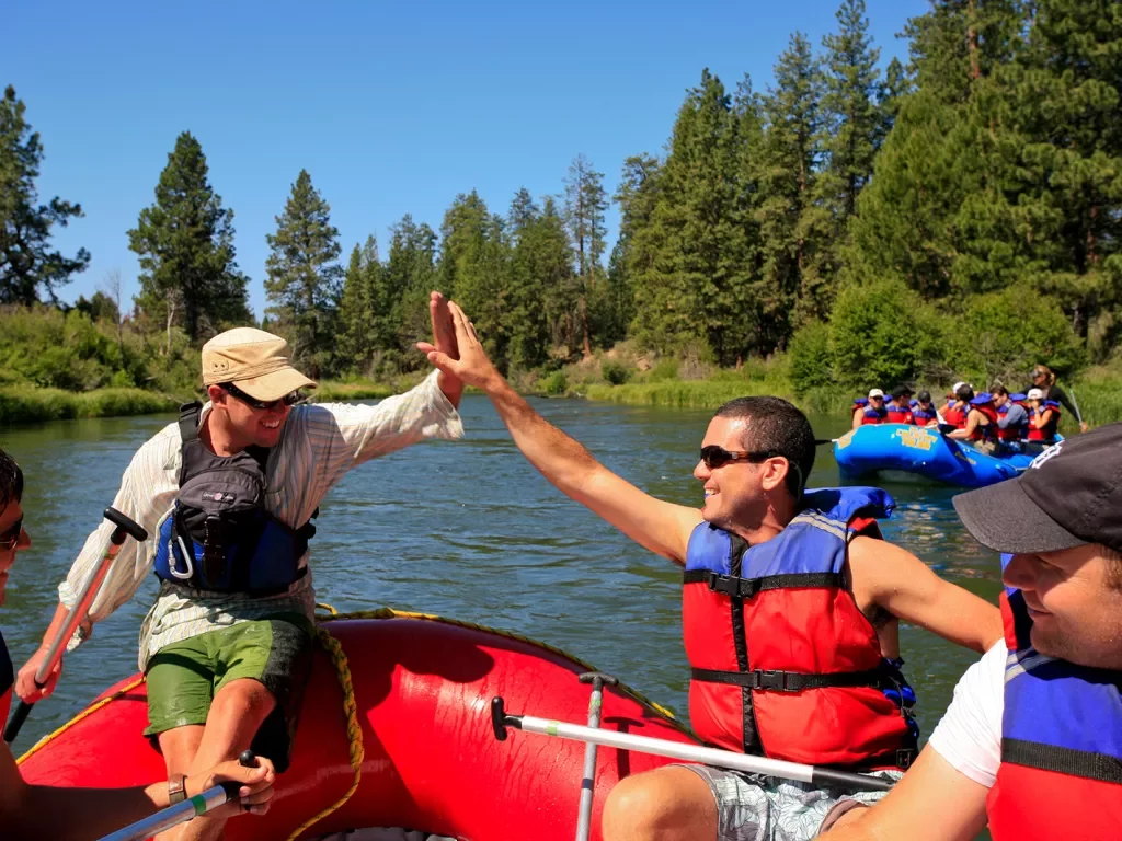 Two guests hi-fiving on rafts.