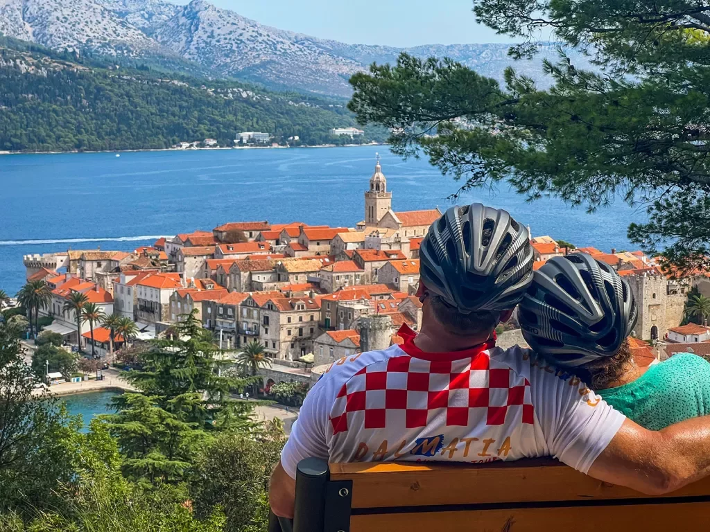Two guests in bike gear on bench, overlooking Dalmatian Coast.