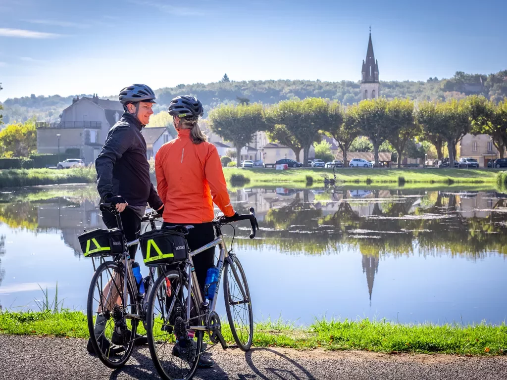 Two guests with bikes looking out towards river, town, hills, church spire.