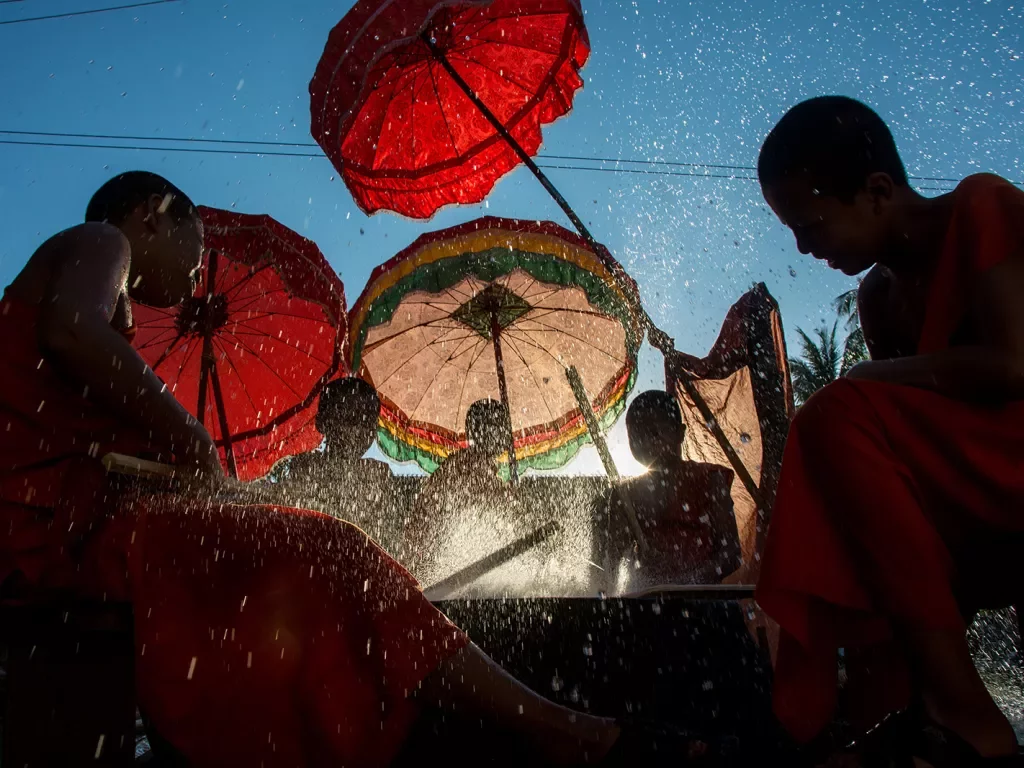 novice monks beating a new dry with palm reeds and splashing water