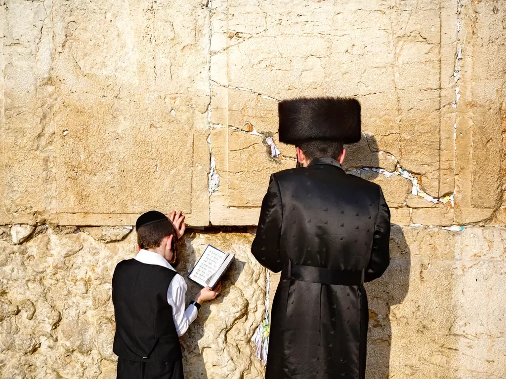 A child and an adult praying at the Western Wall