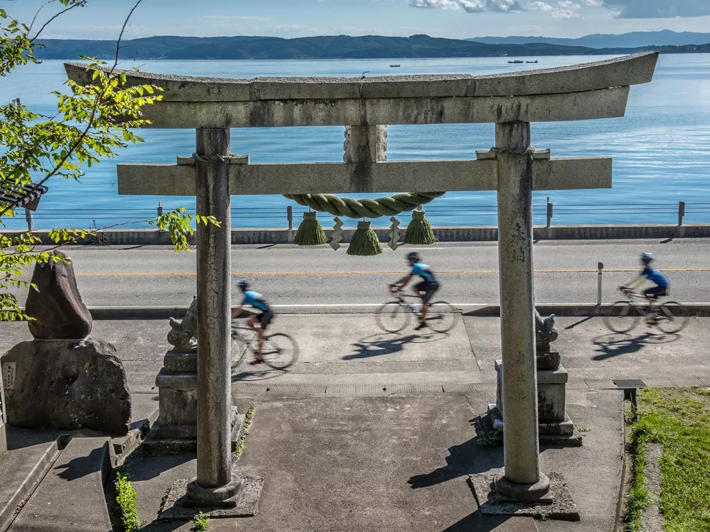 3 Backroads guests biking near body of water and along Japanese structure 