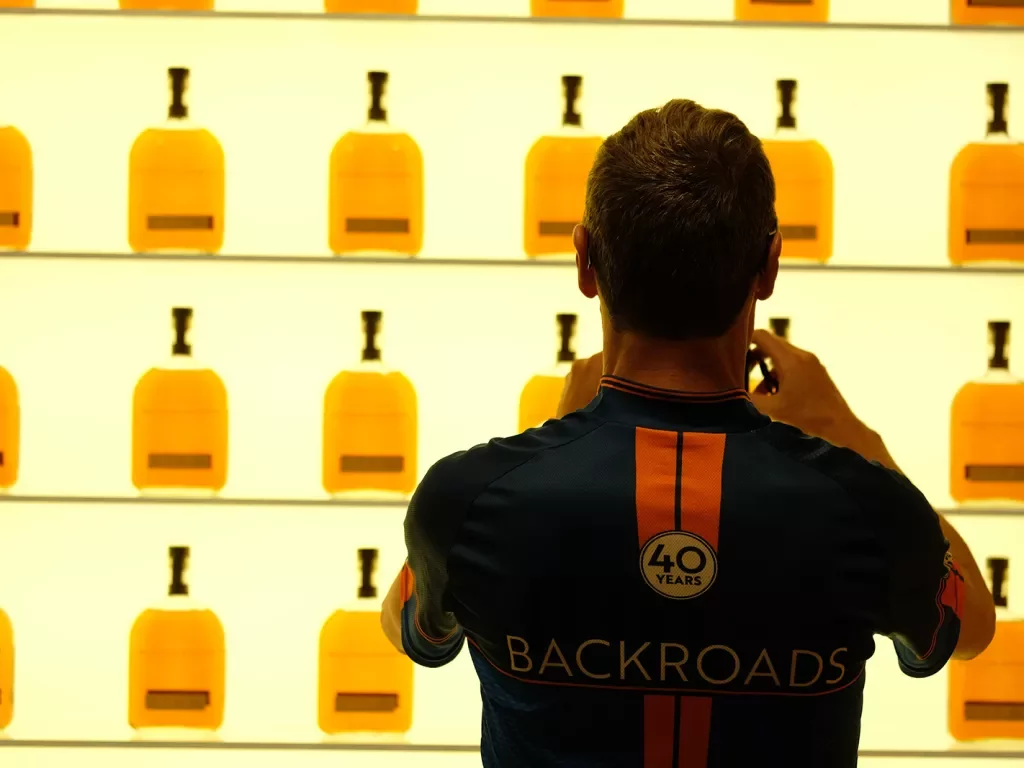 Guest taking photo of wall of whiskey bottles.