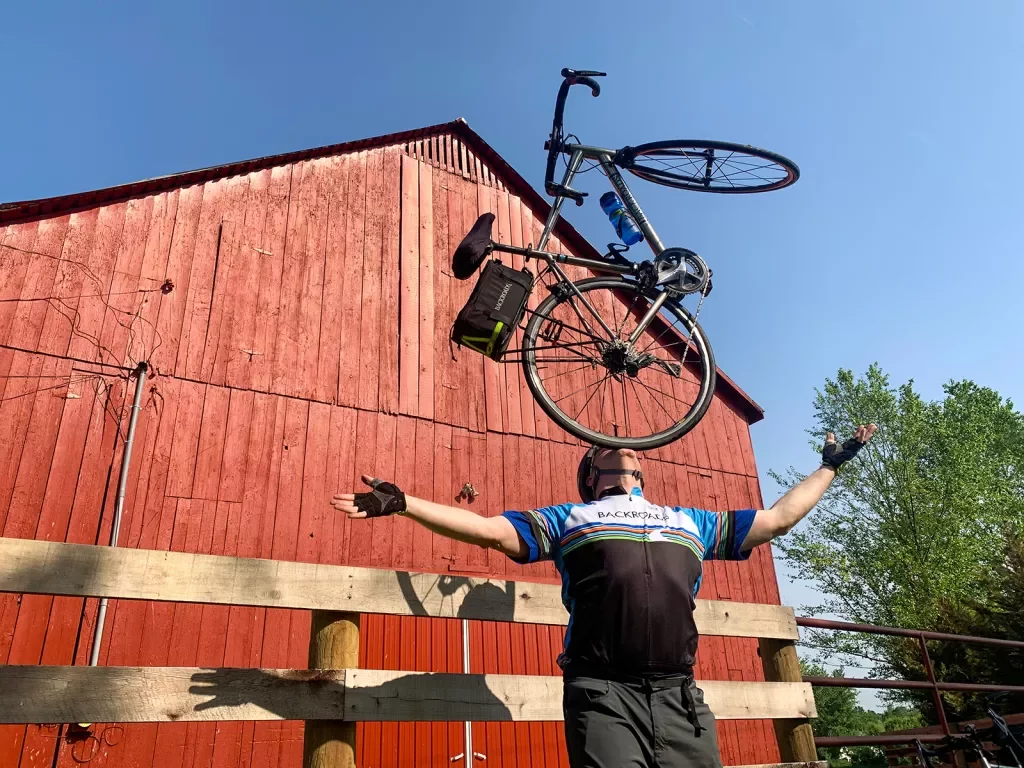 Guest balancing bike on their chin, red barn in background.