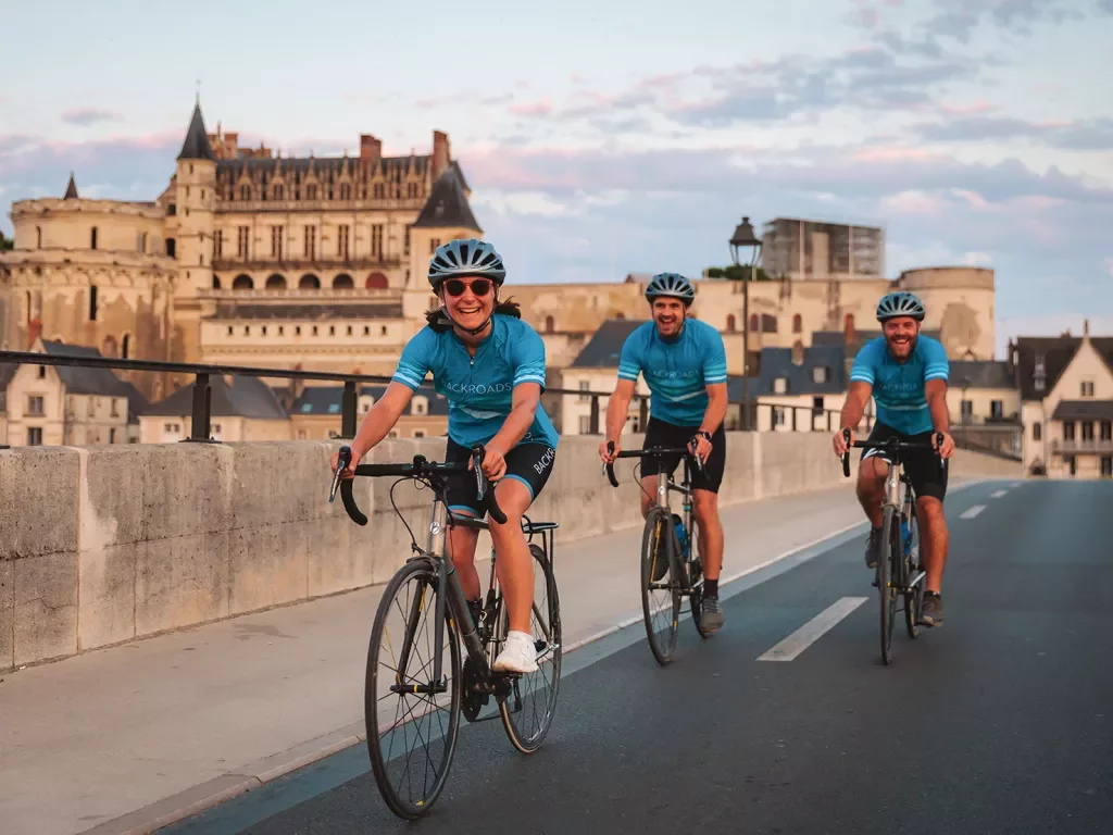 Three guests cycling in French town, Château Royal d'Amboise in background.