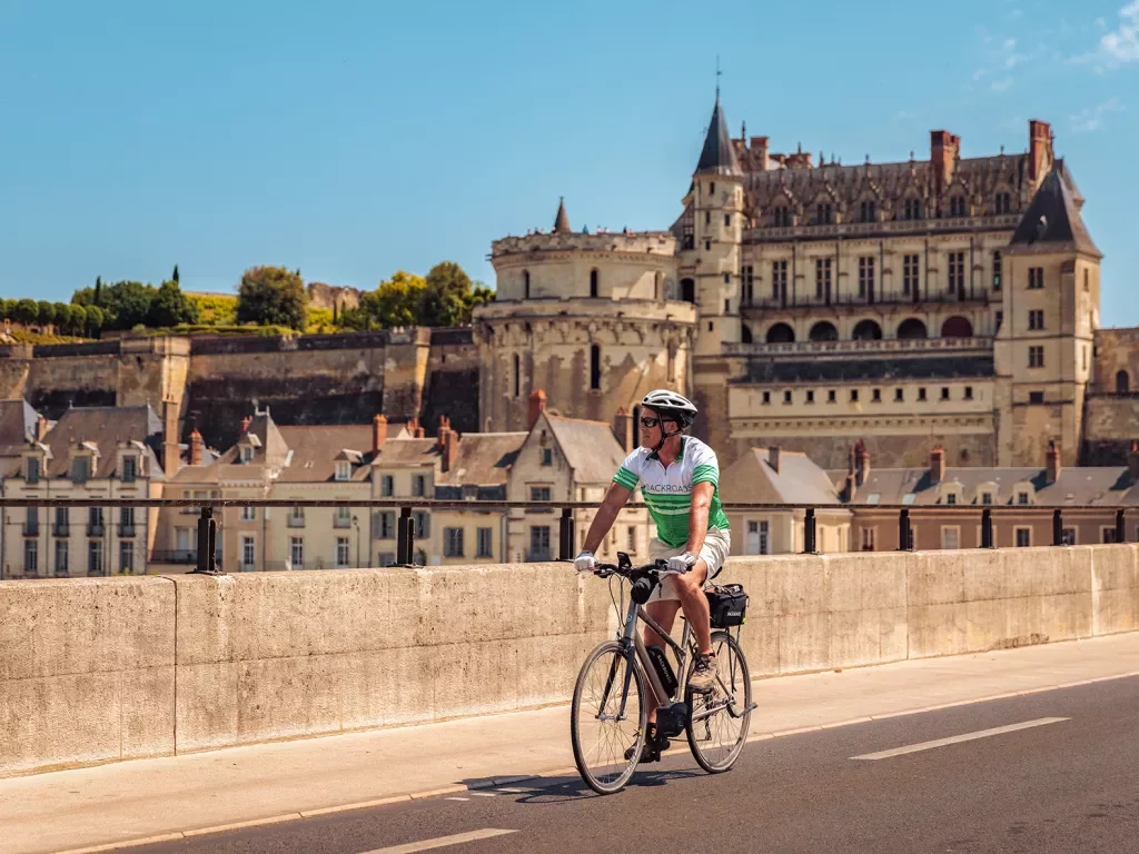 Guest cycling in French town, Château Royal d'Amboise in background.