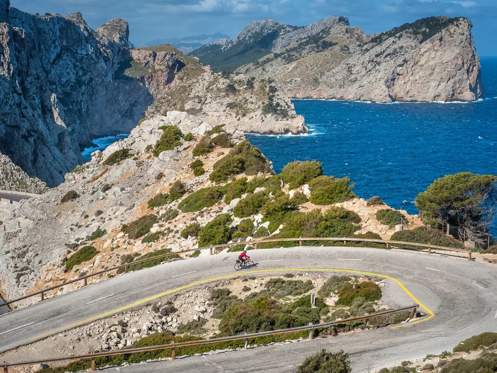 Biker riding around a bend on the coast of Mallorca.