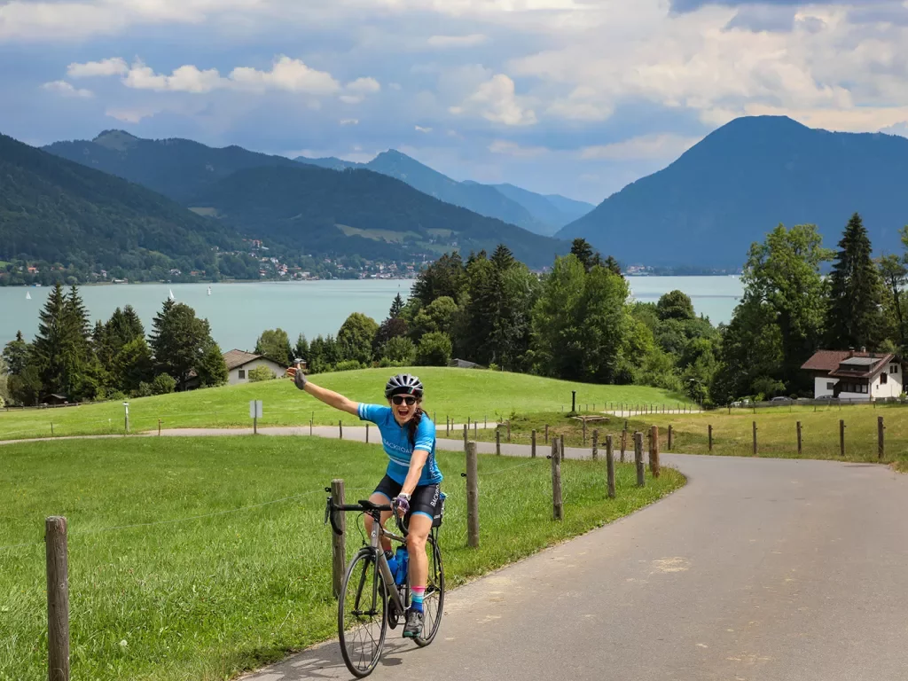 Biker riding on road with scenic German lake in background.