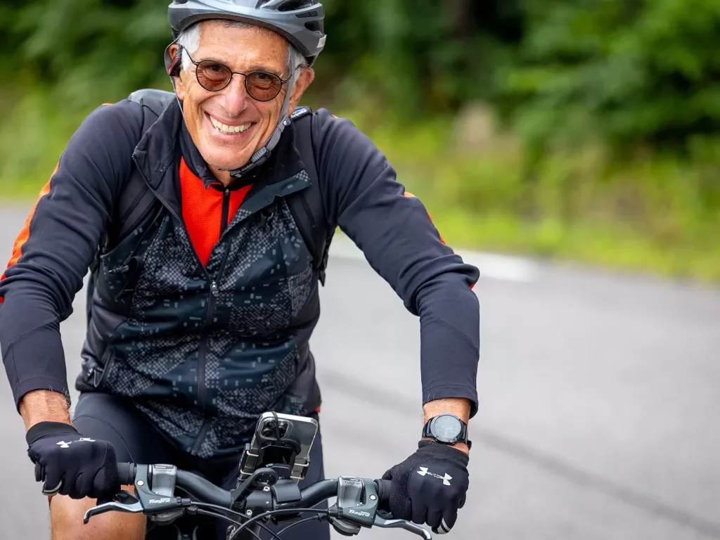 Older biker smiling while riding.