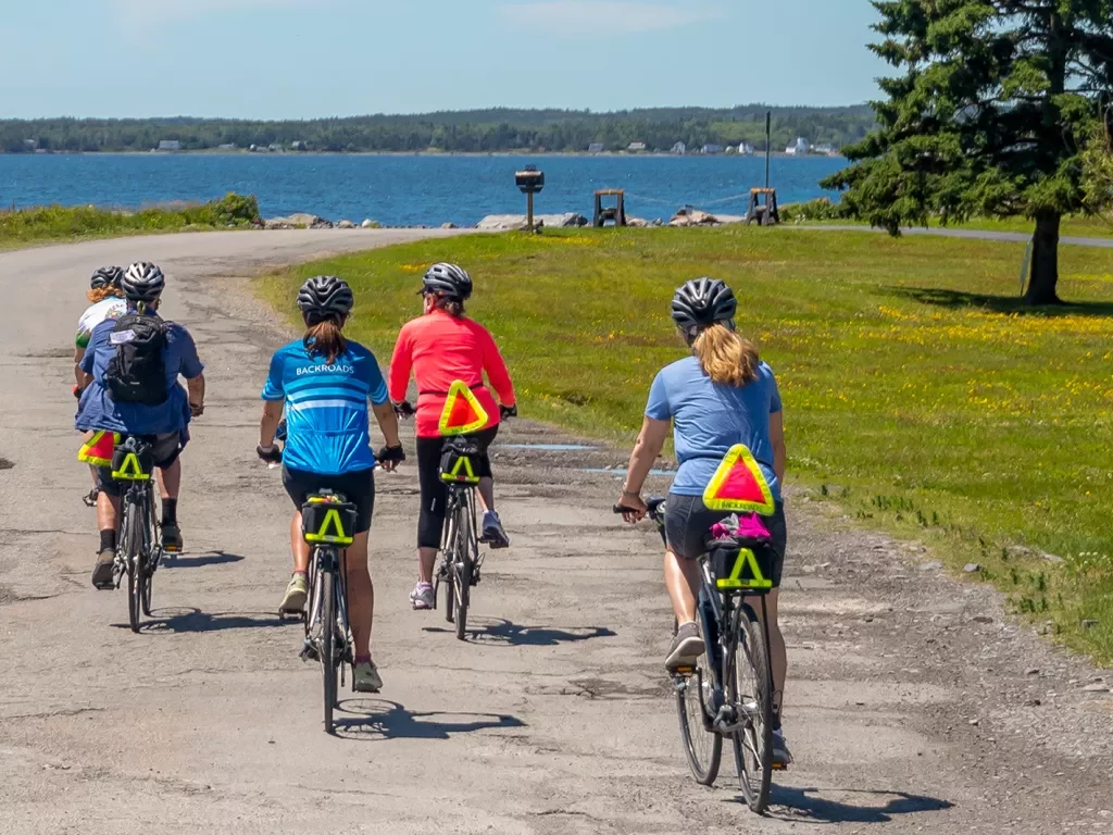 Five guests riding along a coastal trail, ocean to their left.