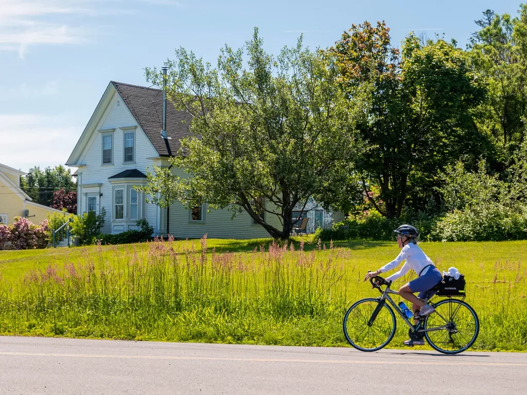 Guest cycling in front of farmhouse and field.