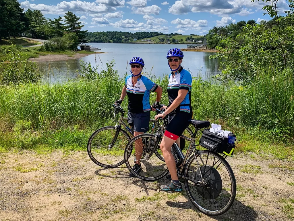 Two guests on their bikes posing in front of small lake.
