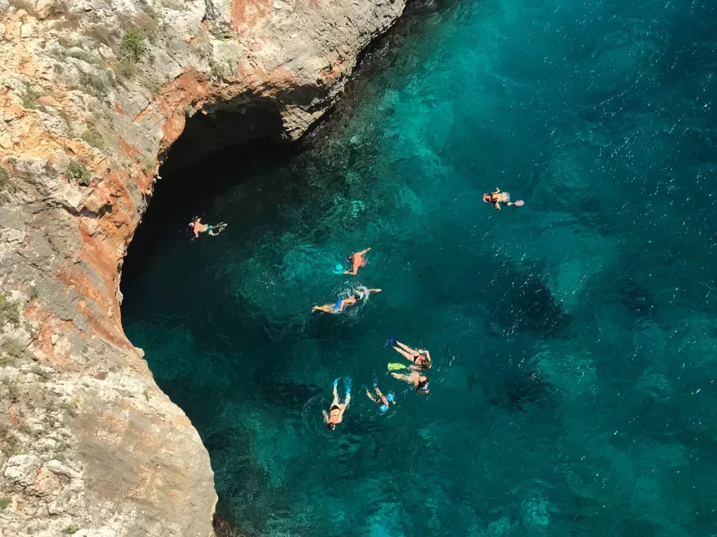 People swimming in a clear blue body of water, Portugal.