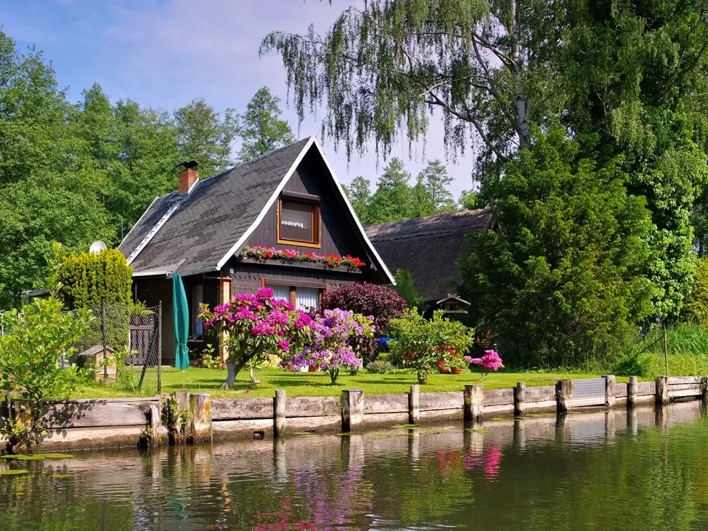 Small wooden cabin with blooming flower garden in front yard.