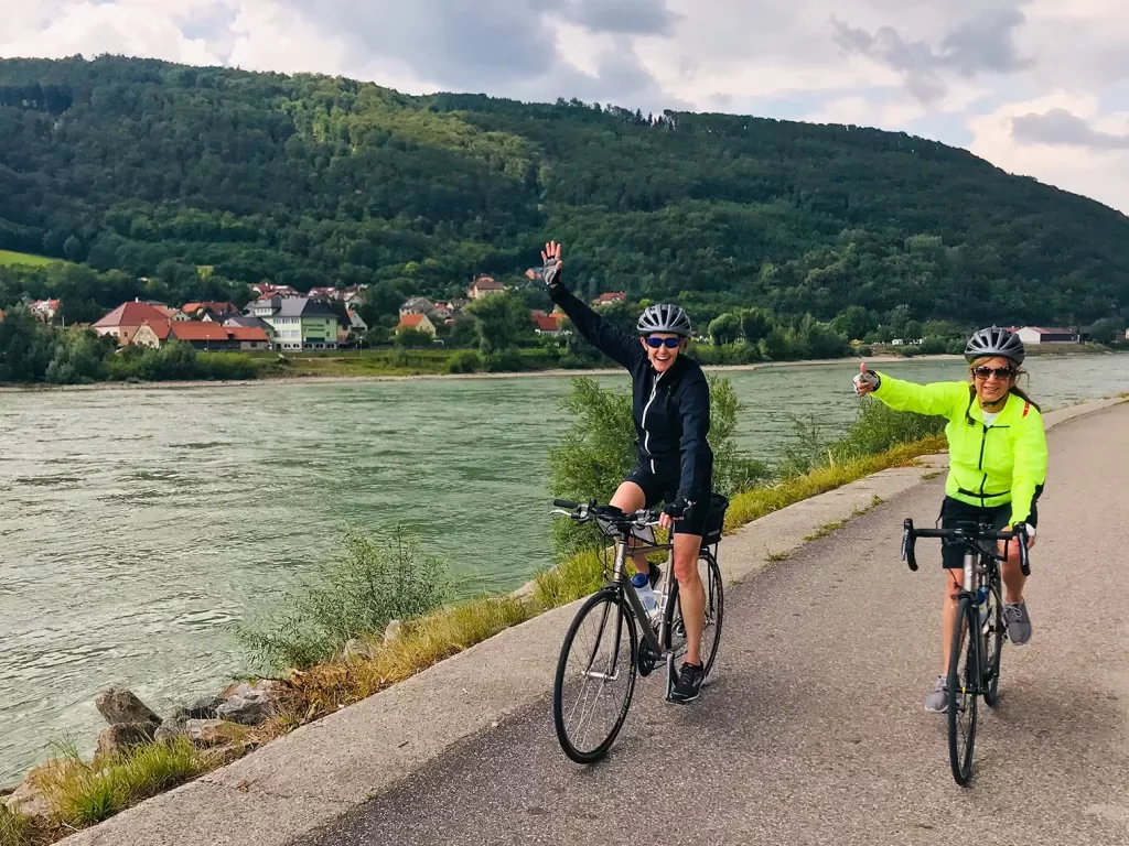 Bikers waving as they ride along riverside