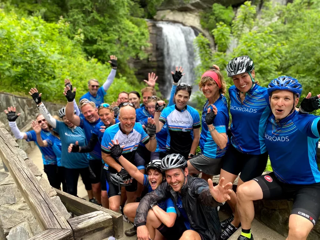Group of guests in biking gear, waterfall behind them.