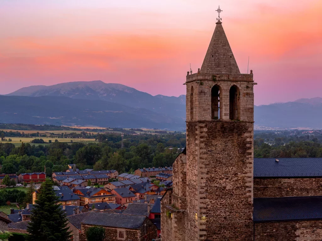 Shot of Spanish village during sunset, large church clock-tower at center.