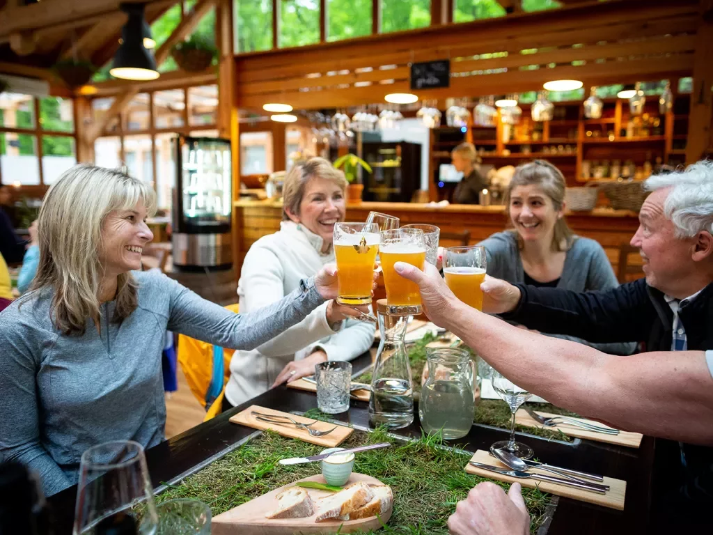 Five guests at meal, cheersing beer glasses.