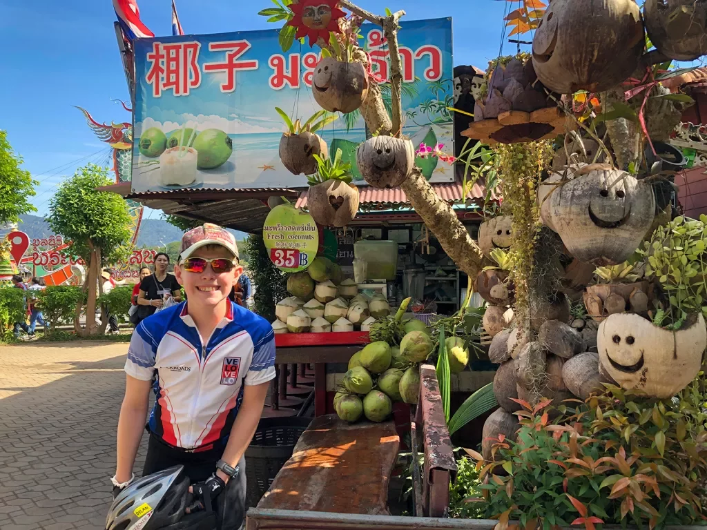 Backroads guest with a bike in front of a fruit stand in Thailand