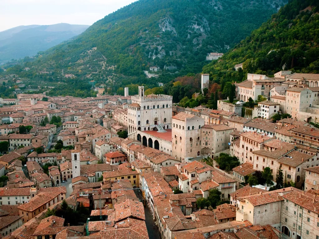 Wide shot of Italian town in valley, terracotta roofing, sandstone brick. 
