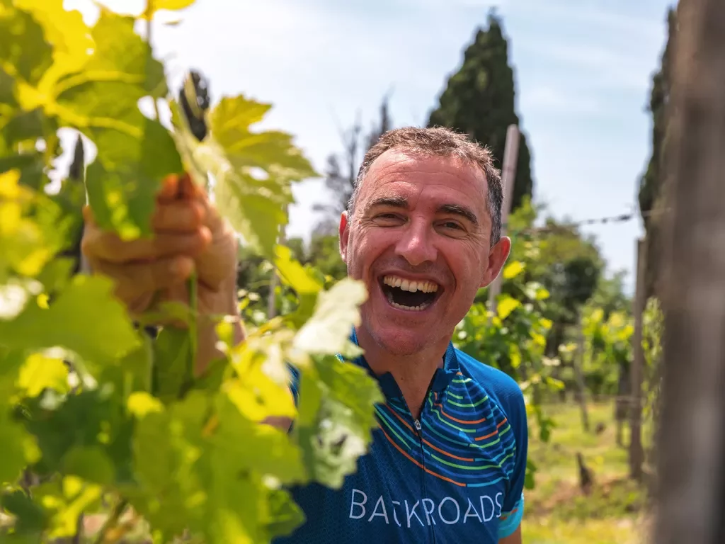 Guest laughing while inspecting grape-vine. 