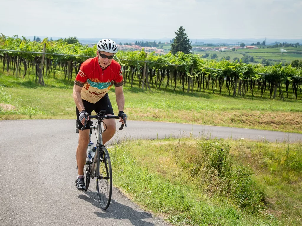 Cyclist riding around a corner with a vineyard in the background