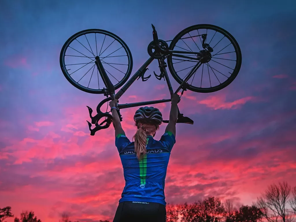 Backroads guest hoisting up bike during sunset