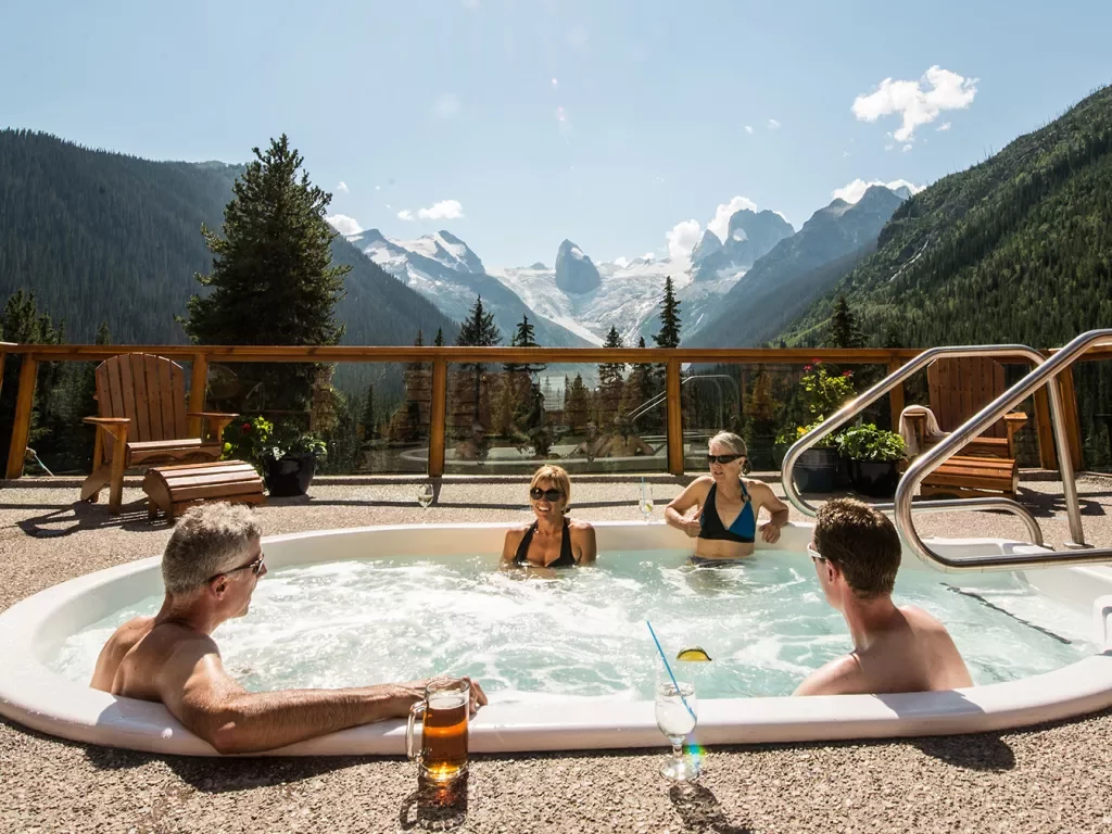 Four guests in hot-tub, mountainous vista behind them.