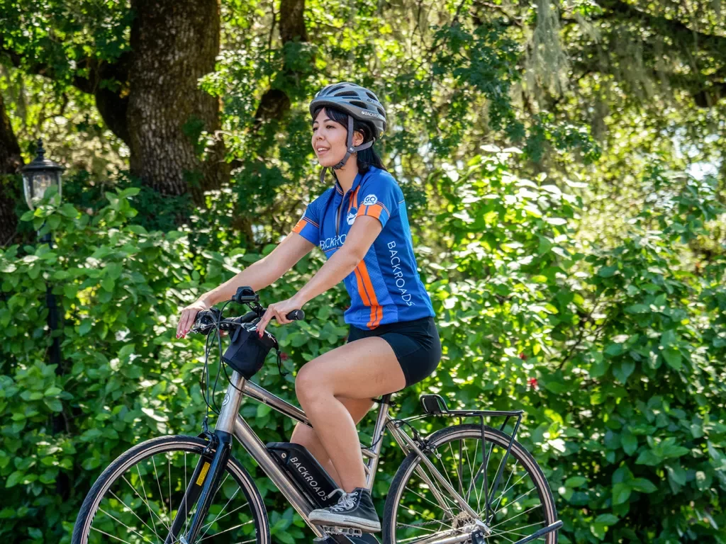 Woman wearing Backroads jersey riding past greenery on a Backroads e-bike